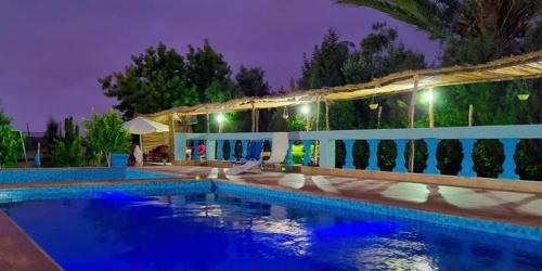 a swimming pool in front of a house at night at auberge touristique zriouila in Guelmim