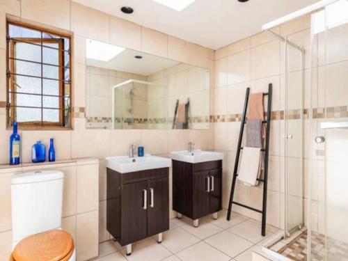 a bathroom with two sinks and a shower and a toilet at 1 Bedroom Cottage in Midrand
