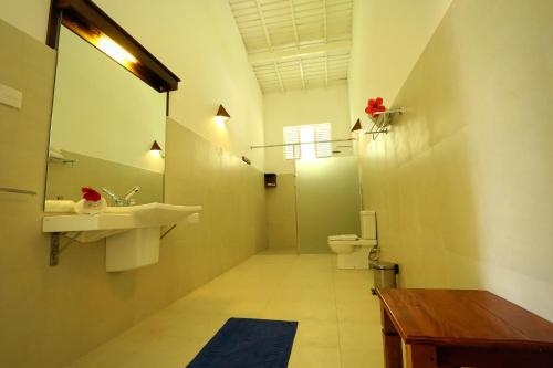 a bathroom with a sink and a toilet and a mirror at Beach Grove Villas in Unawatuna