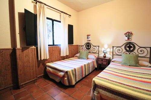 1 dormitorio con 2 camas y TV. en El Precio Justo by SIERRA VIVA en Cortelazor