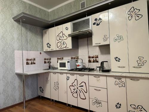 a kitchen with white cabinets and a microwave at Элитная квартира возле гипермаркета Дины in Aktobe