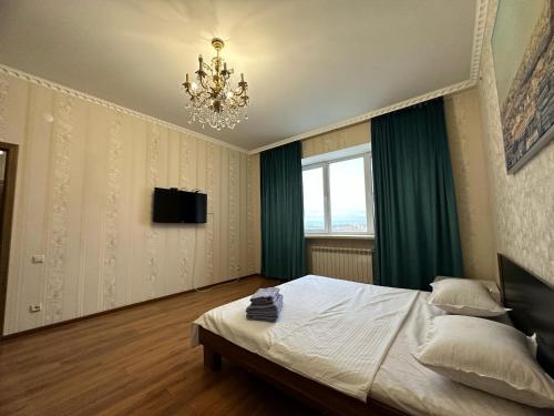 a bedroom with a large bed and a chandelier at Элитная квартира возле гипермаркета Дины in Aktobe