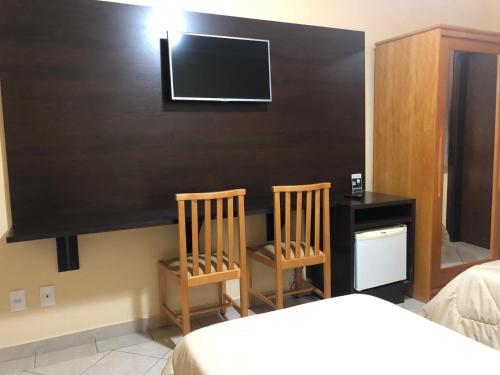 a bedroom with two chairs and a desk and a tv at Hotel Villa de Minas in Monte Sião