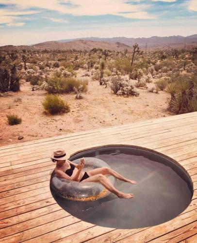 a woman sitting in a hot tub in the desert at Perched on Paradise House in Yucca Valley