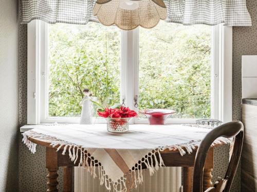 a table in a window with a vase of flowers on it at Holiday Home Angsjö Torp by Interhome in Backaryd