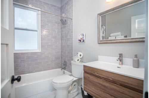 ein Badezimmer mit Waschbecken, Toilette und Spiegel in der Unterkunft Chic Downtown Farmhouse with Garden and BBQ Grill in San Antonio