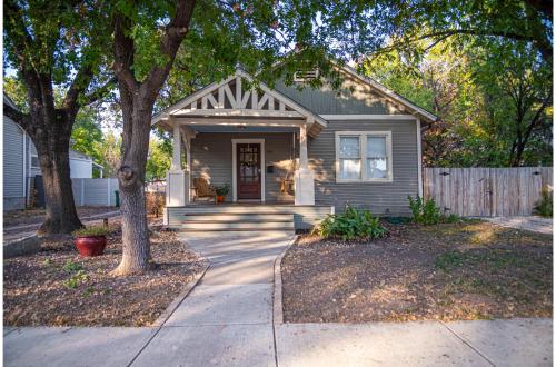 a gray house with a porch and a fence at Chic Downtown Farmhouse with Garden and BBQ Grill in San Antonio