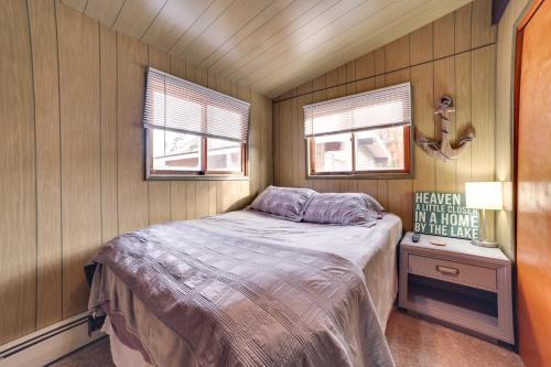 a small bedroom with a bed and two windows at Otsego Lake Getaway with Community Boat Ramp! in Gaylord