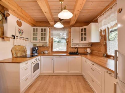 uma cozinha com armários brancos e um tecto de madeira em Świerkowy Raj em Ustroń