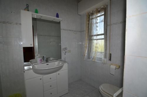 a white bathroom with a sink and a toilet at Casa vacanza Sa Ferula in Flumini di Quartu