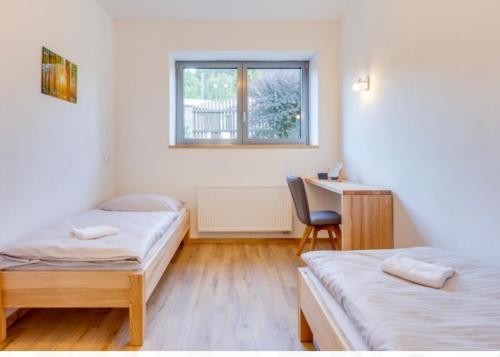 a room with two beds and a desk and a chair at Tilia apartments Březová in Březová