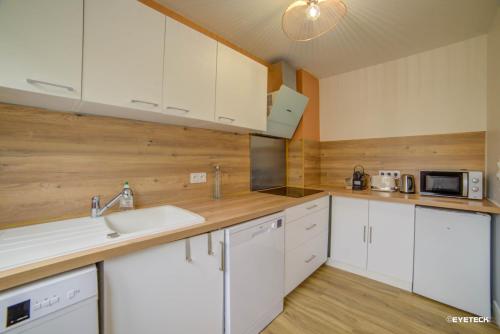 une cuisine avec des armoires blanches et un évier dans l'établissement Bel aparté, design, proche domaine universitaire Turly, à Bourges