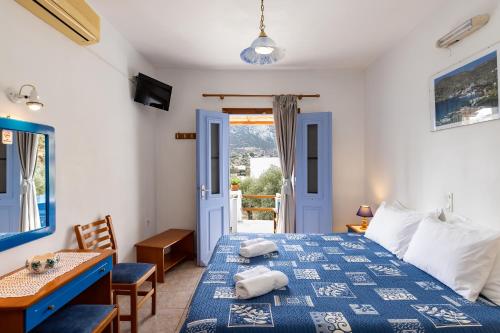 Schlafzimmer mit einem blauen und weißen Bett und einem Schreibtisch in der Unterkunft Katerina Studios Mparou in Apollonia