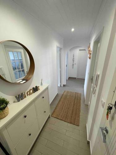 ein Bad mit einem Waschbecken und einem Wandspiegel in der Unterkunft Casa Carvalho in Quinta do Conde