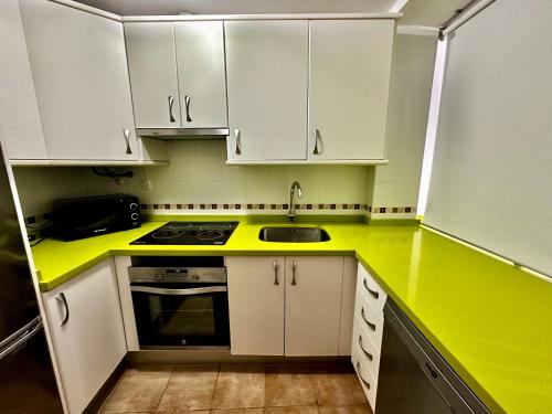 a kitchen with a yellow counter top and white cabinets at Apartamento E&D in Nerja