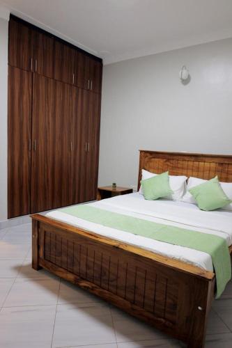 a bedroom with a large wooden bed with green pillows at The residence Ug in Bulindo