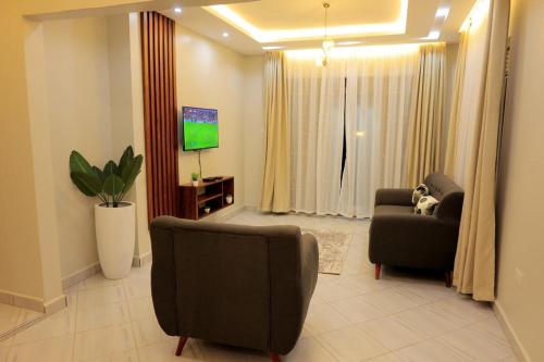 a living room with two chairs and a flat screen tv at The residence Ug in Bulindo