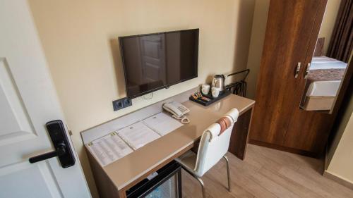 a room with a desk with a phone and a television at MAÇA OTEL in Edirne