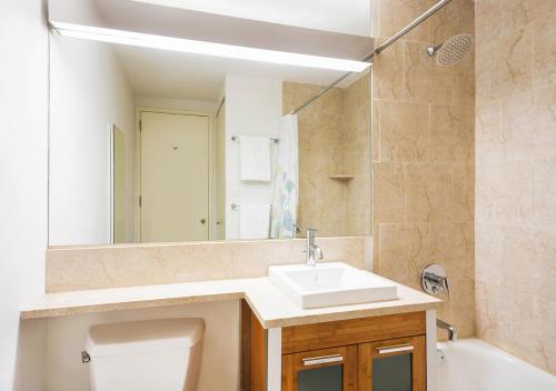 a bathroom with a sink and a toilet and a mirror at Modern Two Bedroom At UES in New York