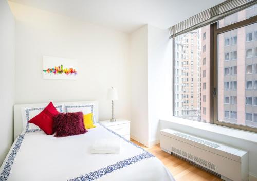 a white bedroom with a bed and a large window at Modern Two Bedroom At UES in New York