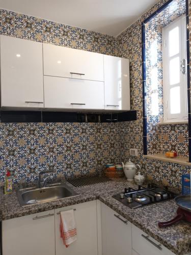 una cucina con armadi bianchi e lavandino di Dar Meriem a Tunisi