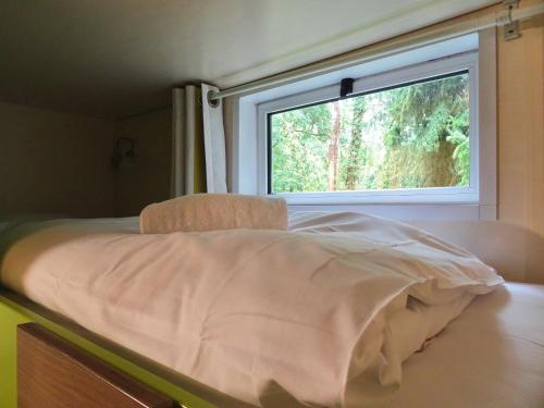 łóżko w pokoju z oknem w obiekcie La Roulotte à 10min de Disneyland Paris - Cabane & Cabanon w mieście Chalifert