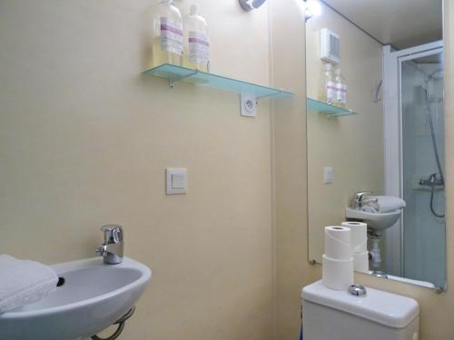 La salle de bains est pourvue d'un lavabo, de toilettes et d'un miroir. dans l'établissement La Roulotte à 10min de Disneyland Paris - Cabane & Cabanon, à Chalifert