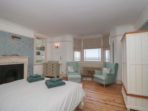a bedroom with a bed and two chairs and a fireplace at 49 Esplanade in Burnham on Sea