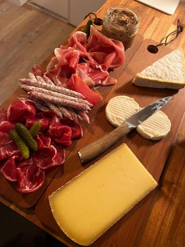 a cutting board with cheese and meats and a knife at Secrète loft in Aucamville