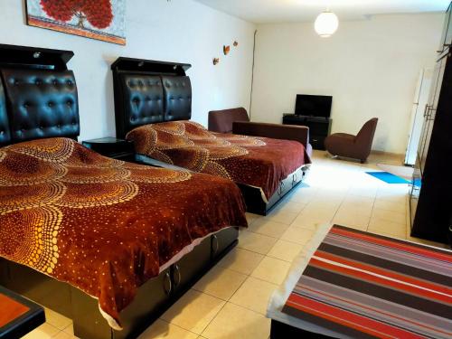 two beds in a room with a room with chairs at Apartamento Centricovive El Pulsar De La Ciudad in Toluca