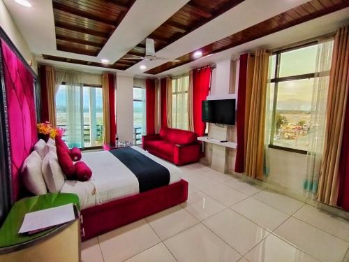 a bedroom with a large bed and a red chair at Swat Hilton Hotel by Khan Familia in Swat