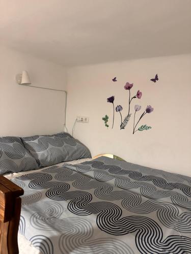 1 dormitorio con 1 cama con flores púrpuras en la pared en as small as caravans, en Viena