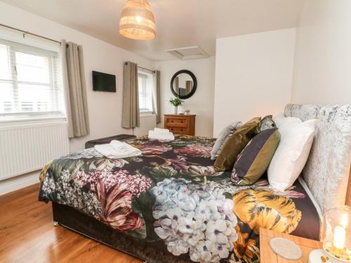 a bedroom with a bed with a floral bedspread at Cosy Cottage in Lifton