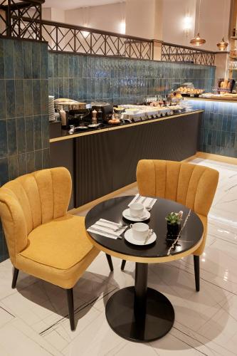 a table and two chairs in a restaurant with a counter at Best Western Premier Hotel des Vignes et des Anges in Pauillac