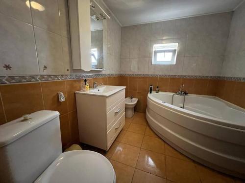a bathroom with a toilet and a tub and a sink at Vila 8 oaspeti in Bucharest