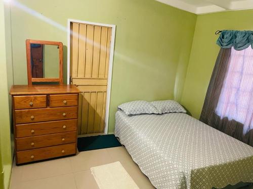 um quarto com uma cama, uma cómoda e um espelho em St Eldo em Arima
