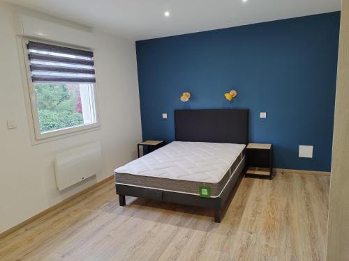 een slaapkamer met een bed en een blauwe muur bij Gîtel'harmonie2 in Fraize