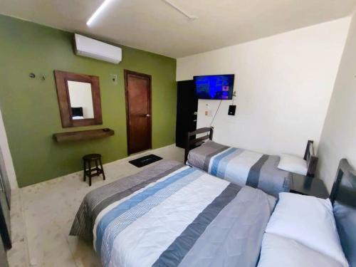 um quarto de hotel com duas camas e uma televisão em Casa Olivo, tranquilidad y descanso. em Mérida
