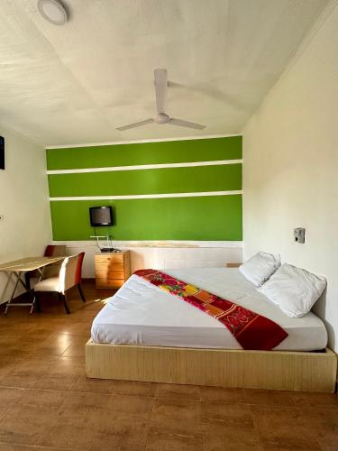 una camera con un letto con una parete verde di My Place Guest House a Ho