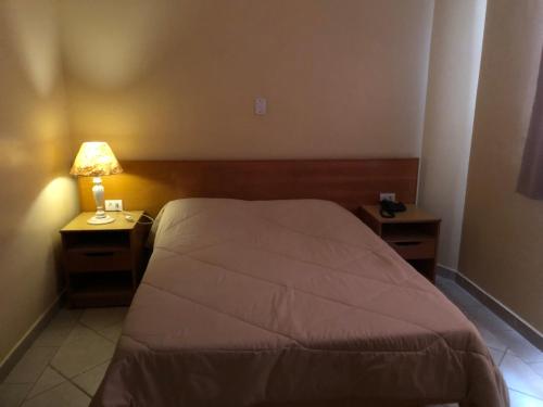 a bedroom with a bed and two night stands with a lamp at Hotel Villa de Minas in Monte Sião