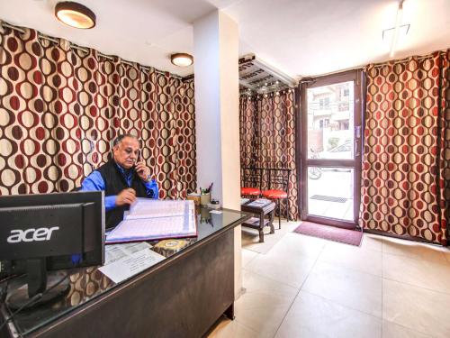 a man talking on a phone at a desk in an office at OYO Hotel Shiv Shakti Inn Near Kamal Cinema in New Delhi