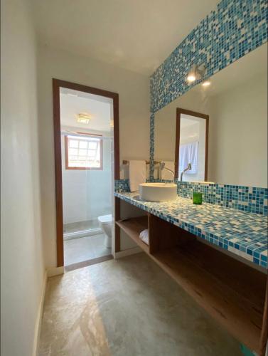 a bathroom with a sink and a mirror and a toilet at Casas Loft Búzios in Búzios