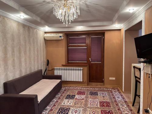 a living room with a couch and a chandelier at Апартаменты напротив аэропорта in Turksib