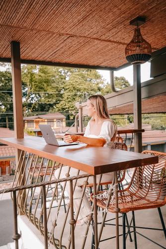 a woman sitting at a table with a laptop at La Fortuna Lodge by Treebu Hotels in Fortuna