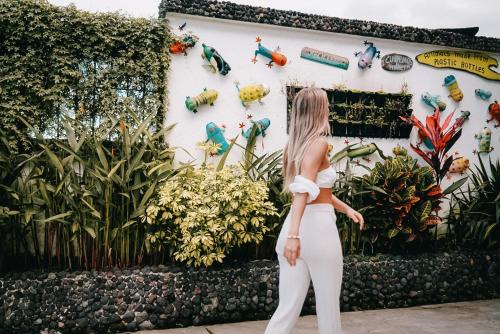 a woman standing in front of a wall of plants at La Fortuna Lodge by Treebu Hotels in Fortuna