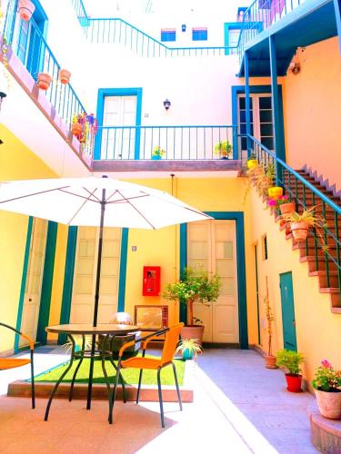 a table and chairs with an umbrella in front of a building at CASONA SANTA MARTA in Arequipa