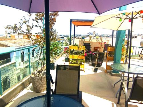 a balcony with tables and an umbrella on a roof at CASONA SANTA MARTA in Arequipa