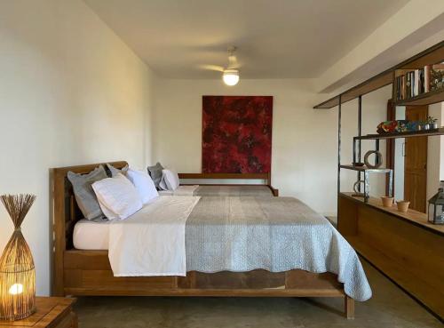 1 dormitorio con 1 cama y una pintura roja en la pared en Casas loft em Armação dos Búzios, en Búzios