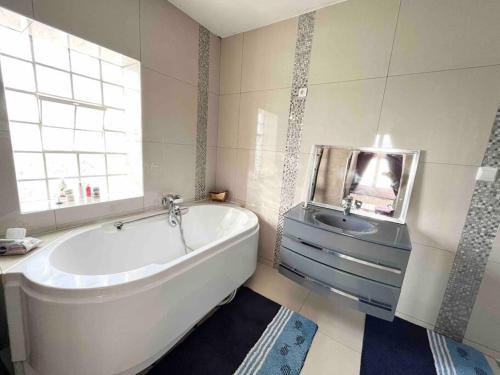 een witte badkamer met een bad en een wastafel bij Demeure - Haut Standing 11min Paris CDG in Dammartin-en-Goële