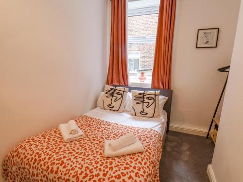 een slaapkamer met een bed met oranje gordijnen en een raam bij 4 Boulby Bank Top in Whitby